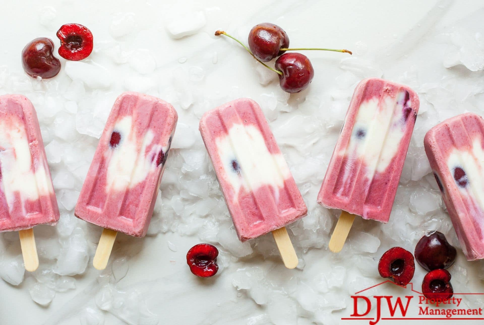 Pink popsicles and cherries on a marble countertop.
