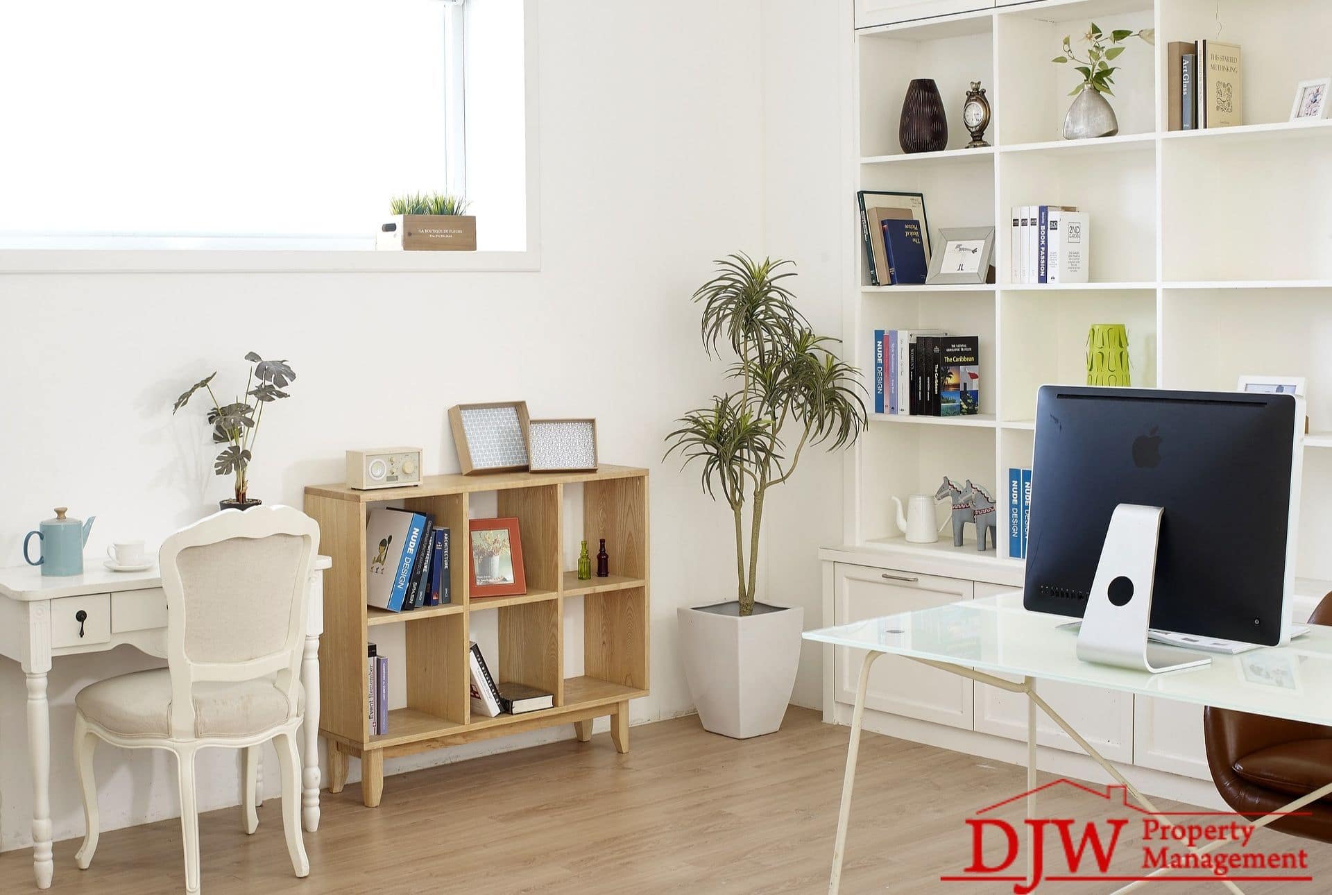 A small, organized room. Built-in shelves line one wall, and two desks and cubicles supply more organization.