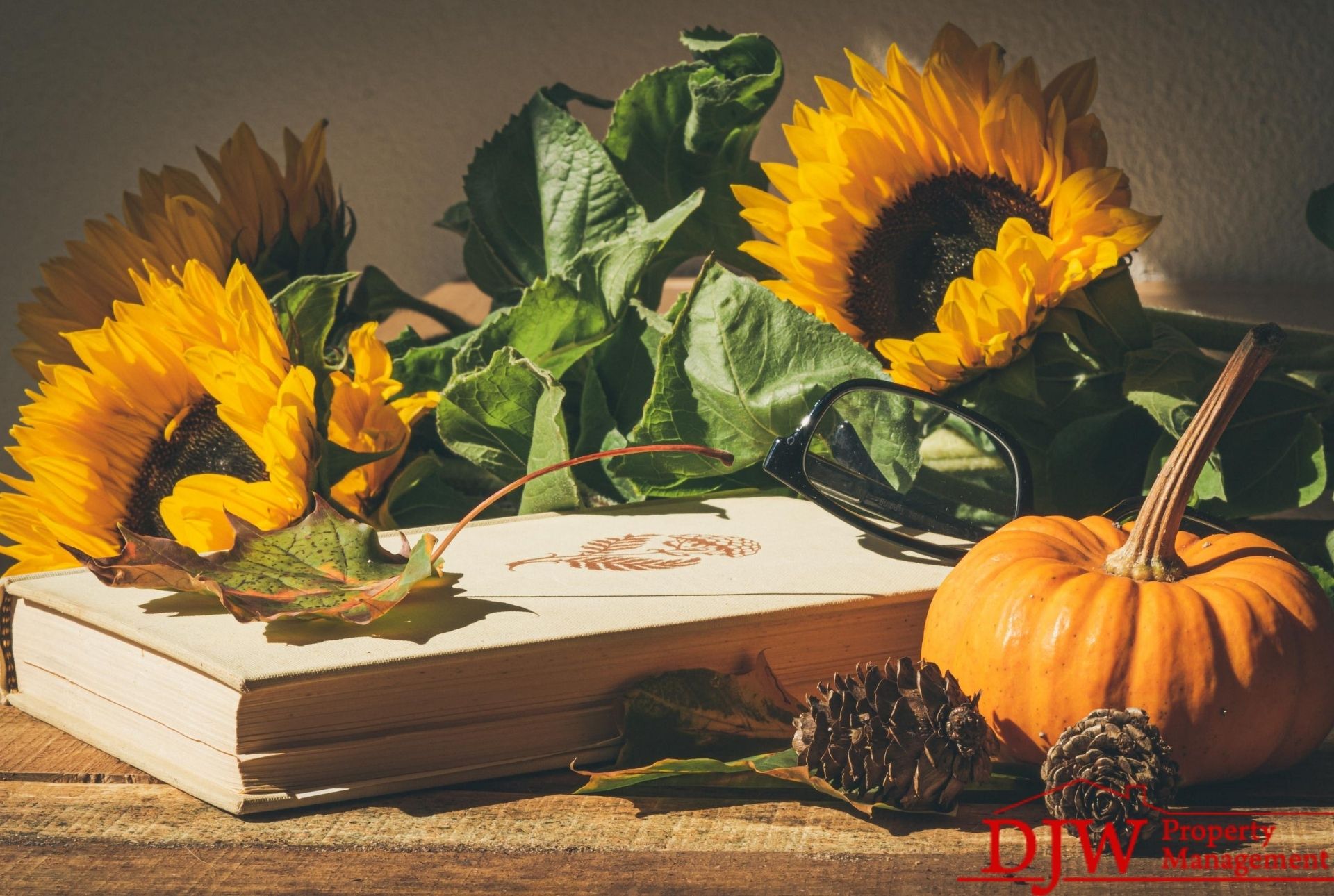 Sunflowers rest on a book. A small pumpkin sits beside them.