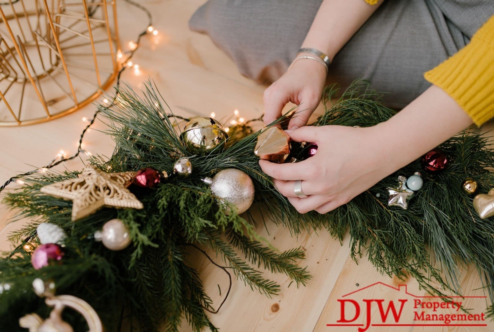 A woman makes a wreath from garland, twinkle lights, and tree ornaments.