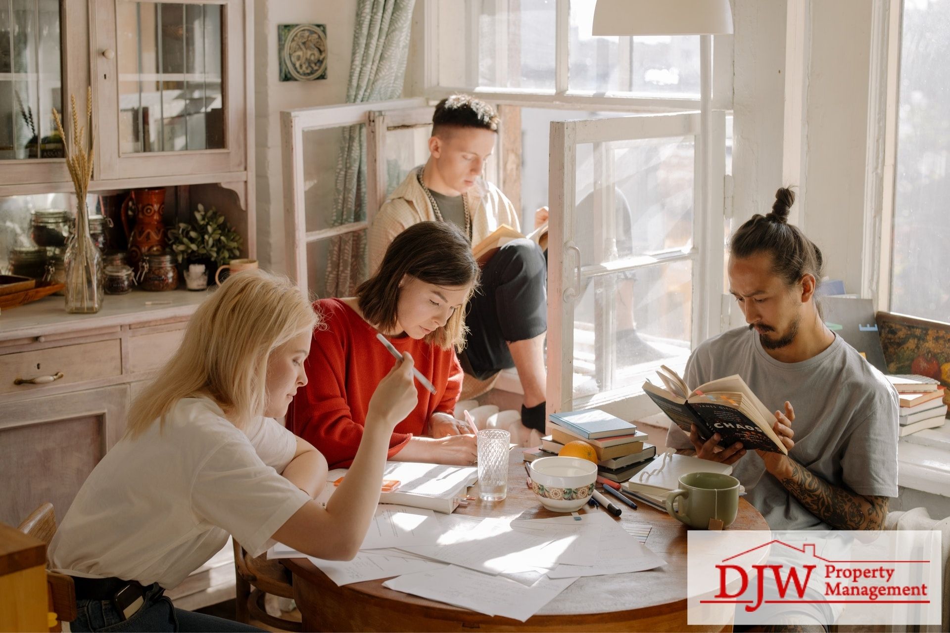 Four college students doing homework around the dinner table in their rental.