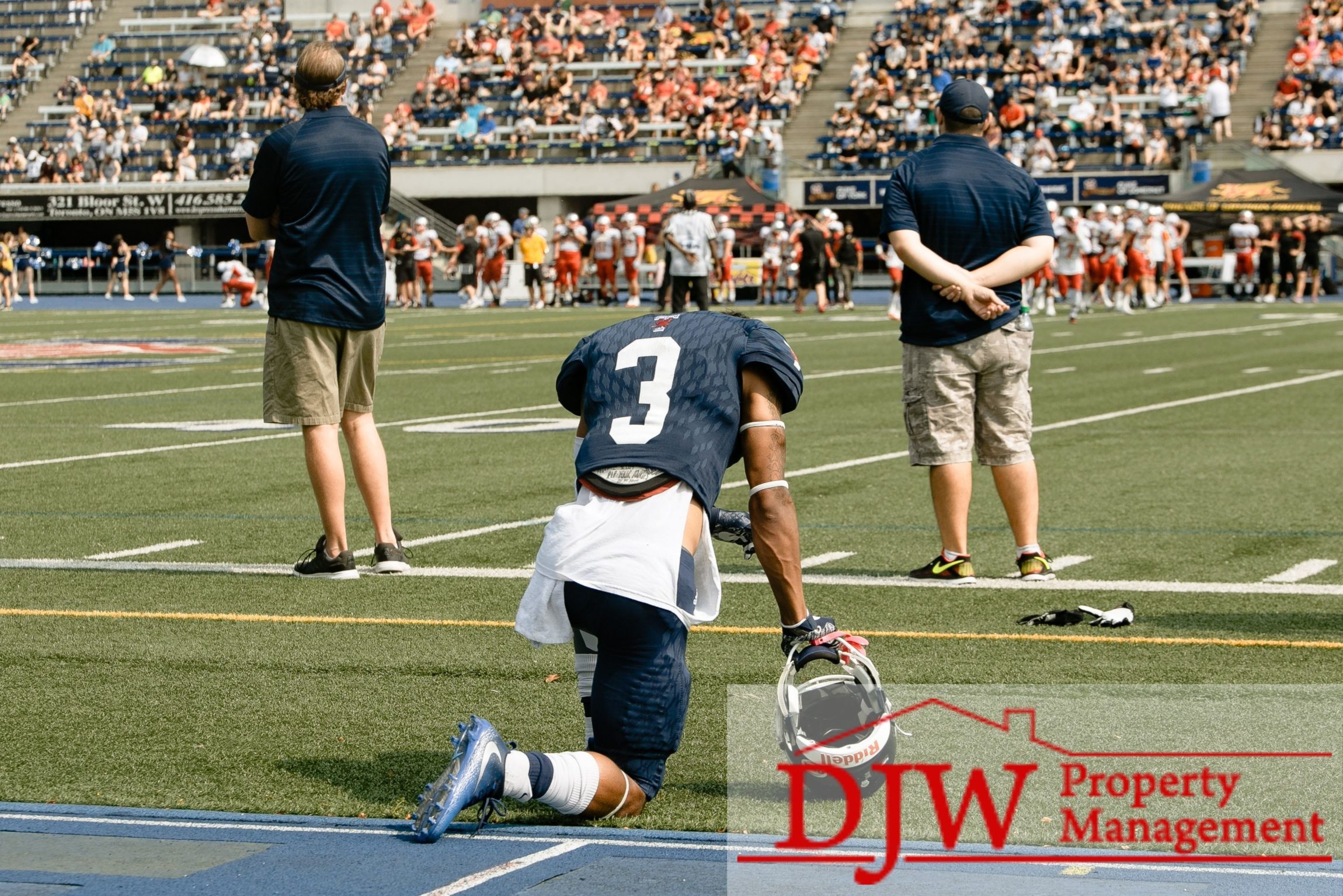 Football player taking a knee on the sidelines.