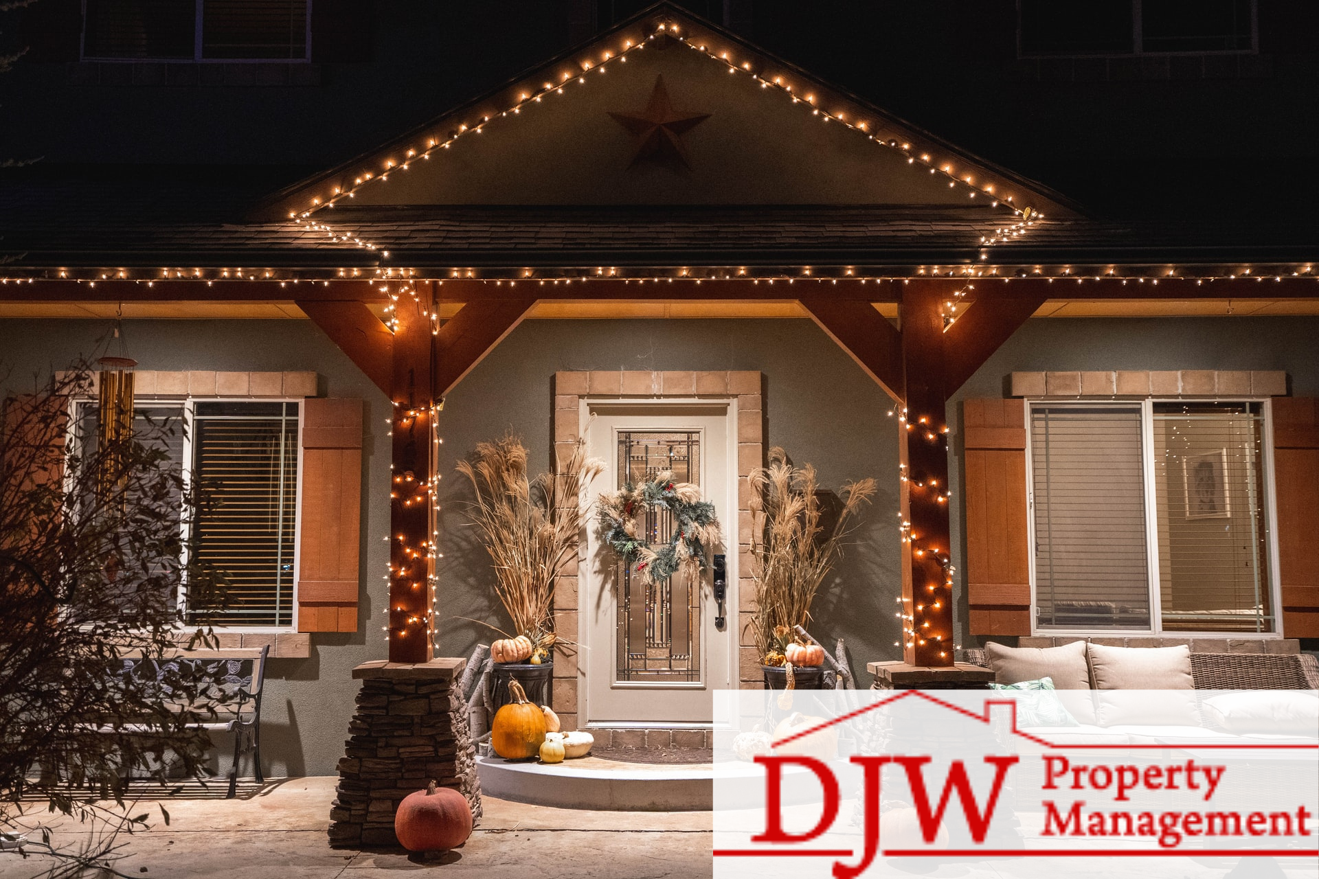 A home decorated with orange lights and pumpkins on its porch.