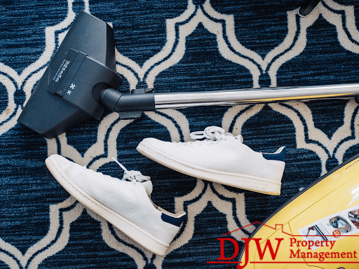 A vacuum and two white shoes sitting on top of a blue and white patterned carpet.